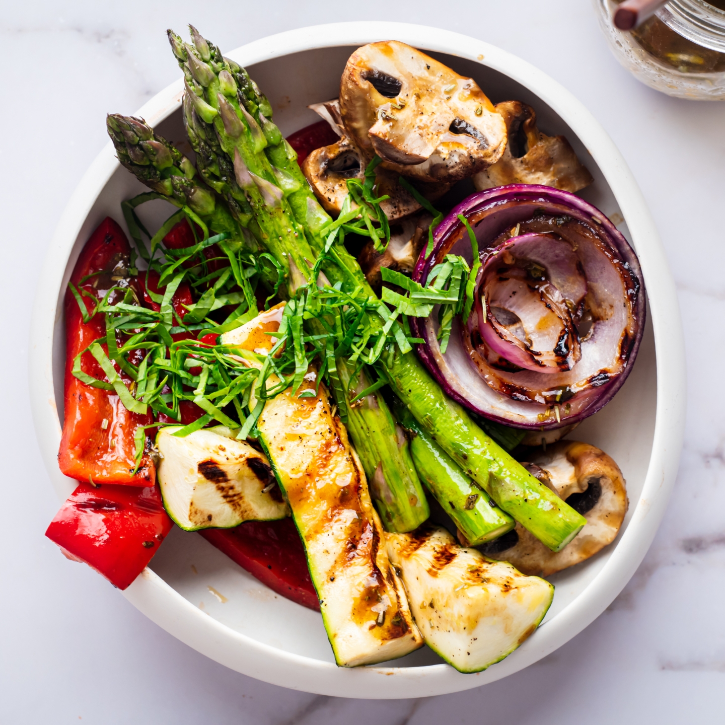 Grilled marinated vegetables with balsamic marinade in a white bowl.