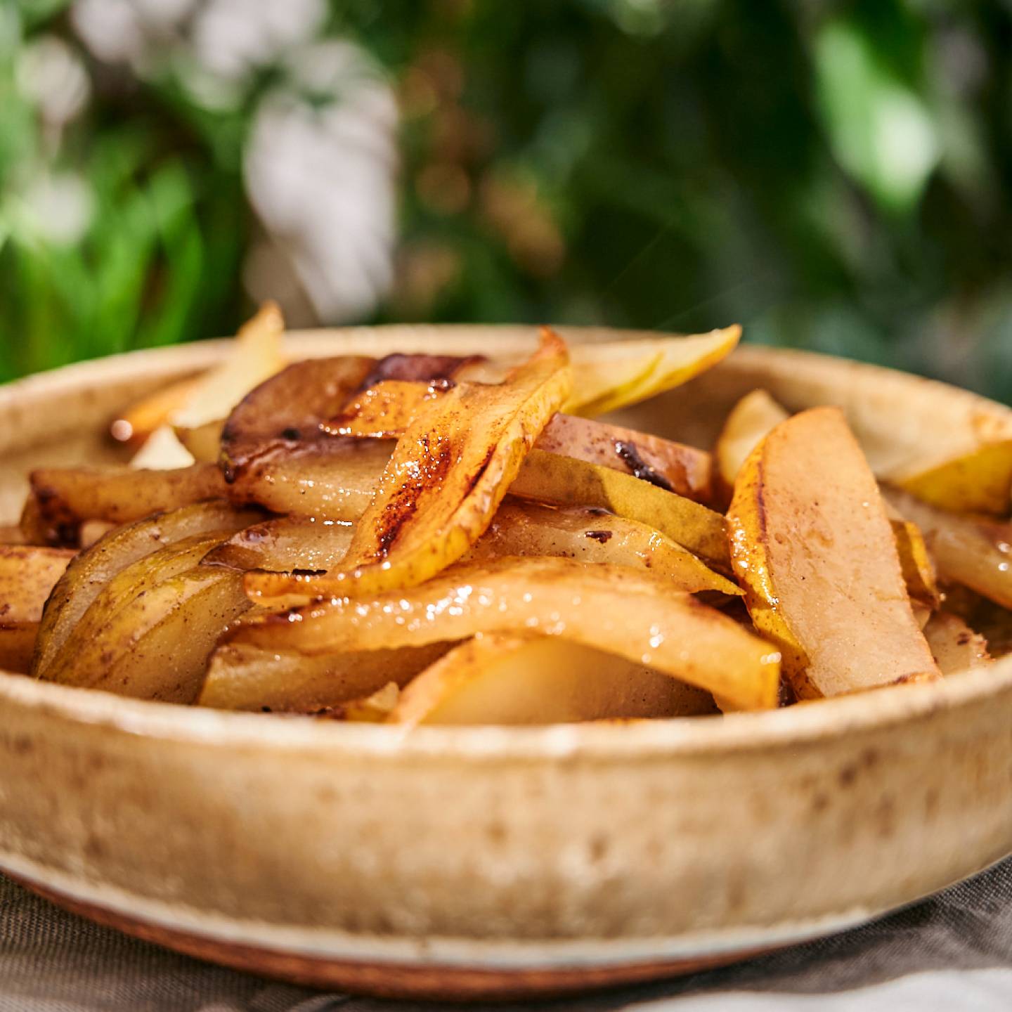 Grilled pears cut into slices with caramelized edges in a white bowl.