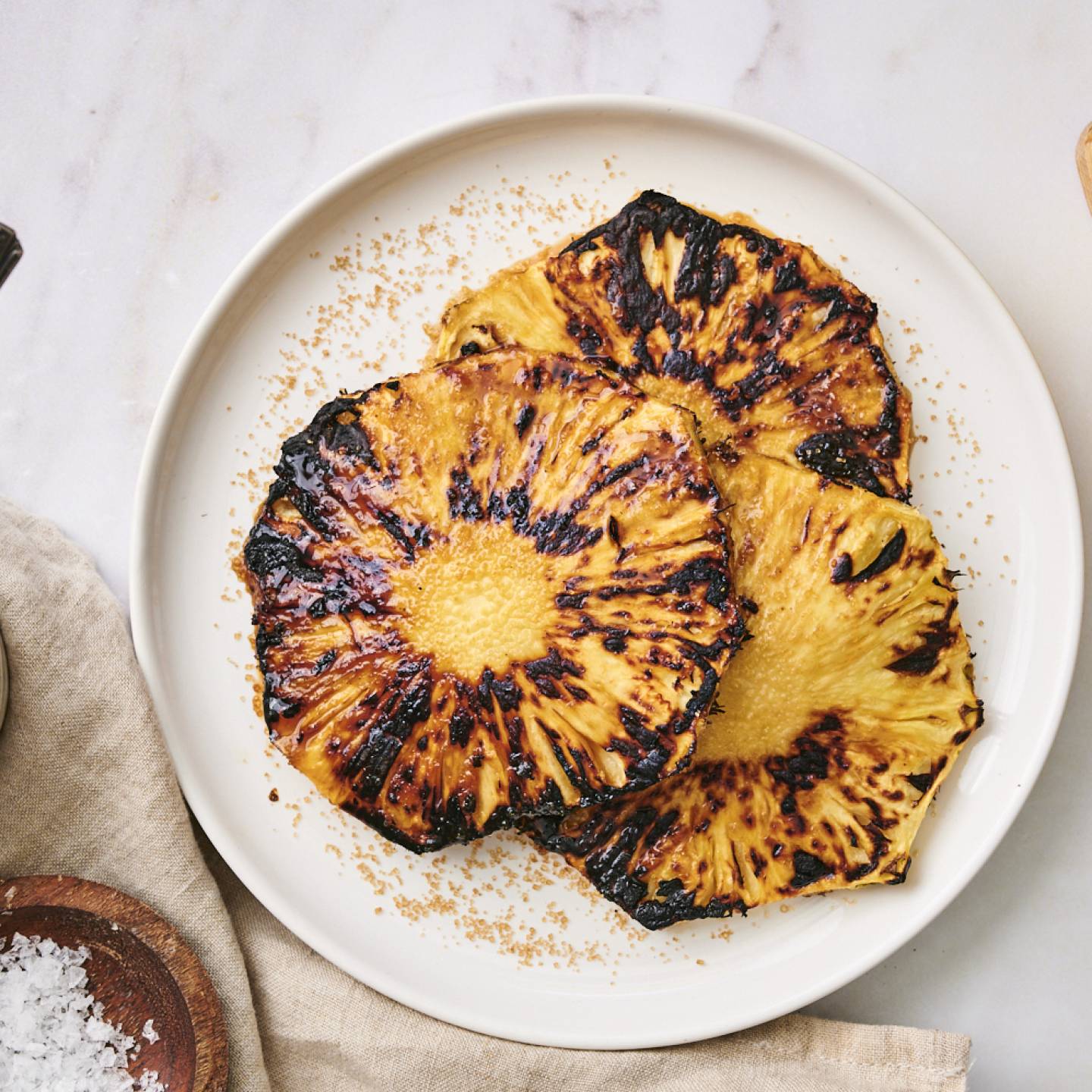 Grilled pineapple with brown sugar and flaky sea salt on a plate. 