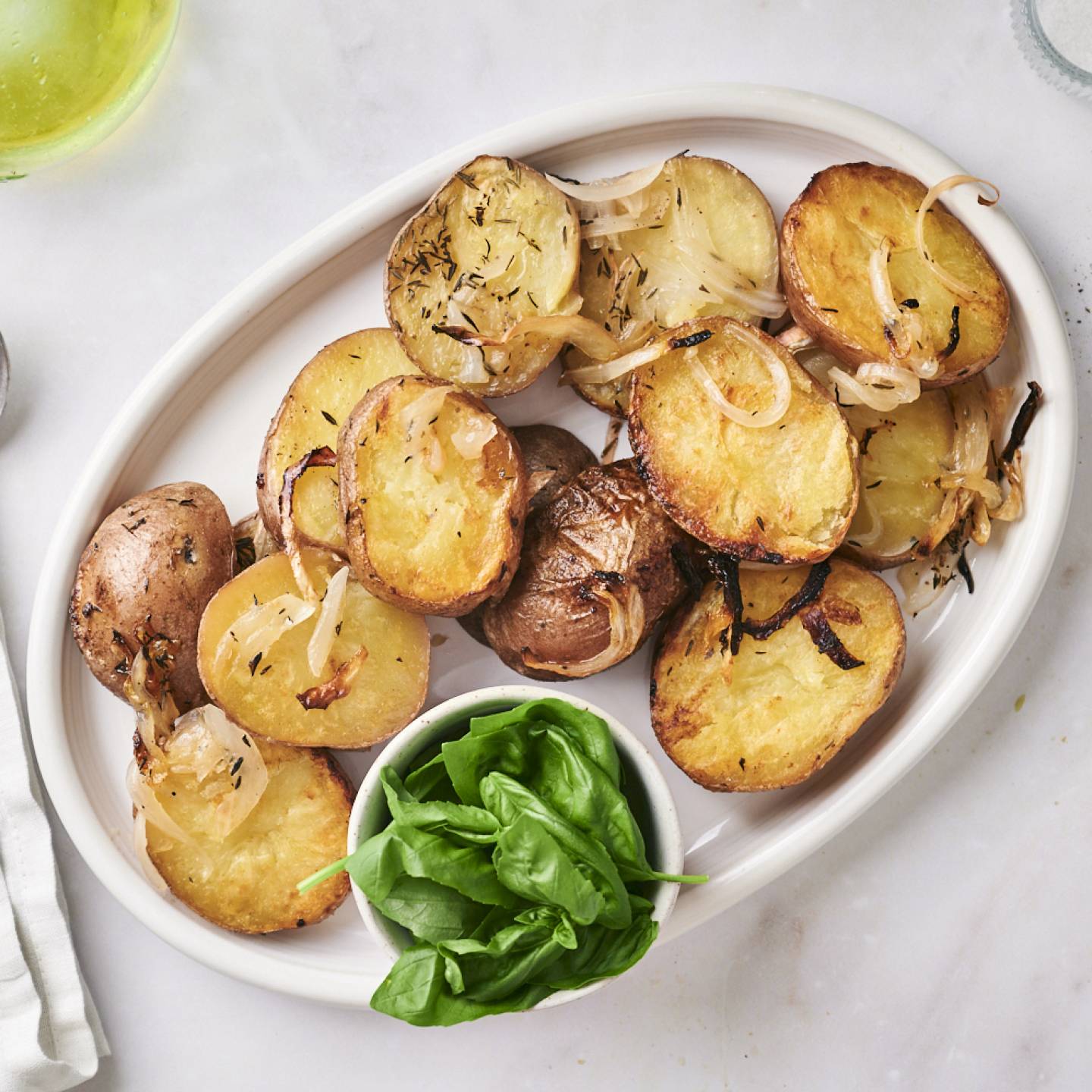 Grilled red potatoes with olive oil, salt, pepper, and onions served on a white plate.