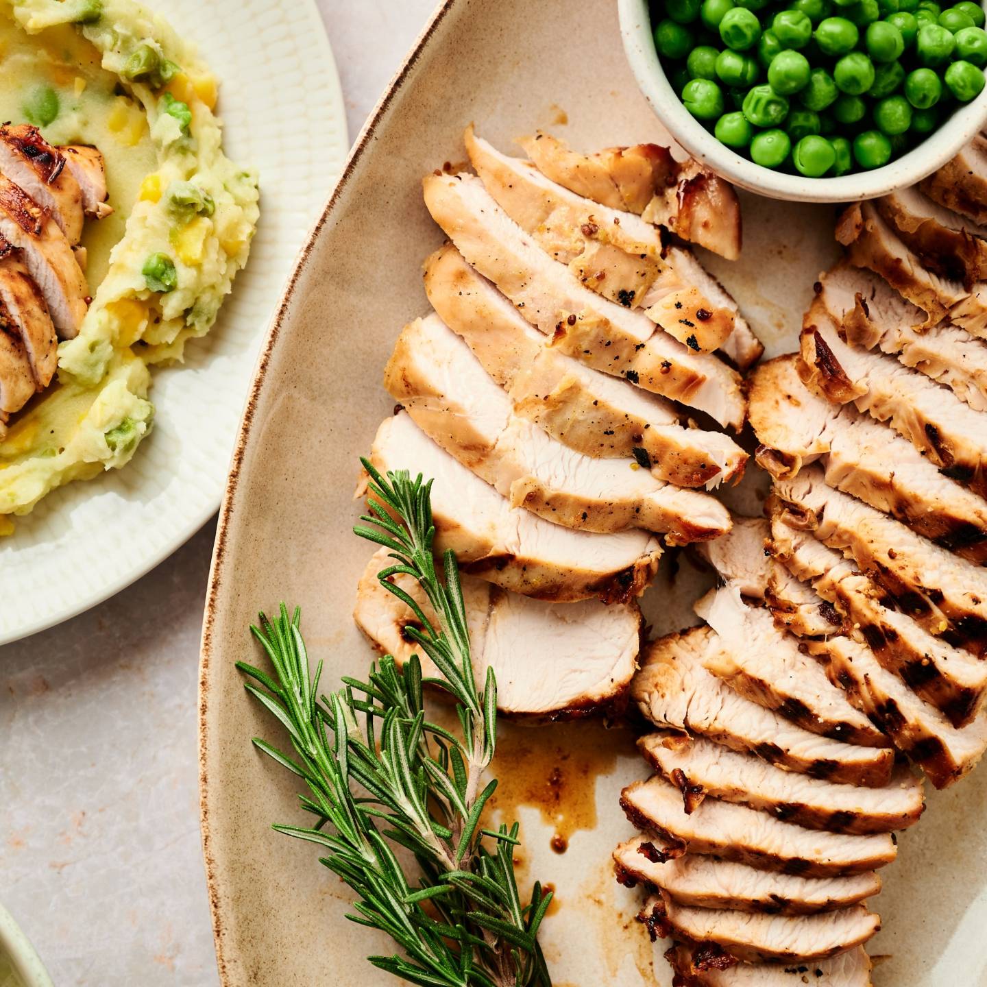 Grilled turkey breast tenderloin served with maple mustard marinade on a plate with peas and rosemary.