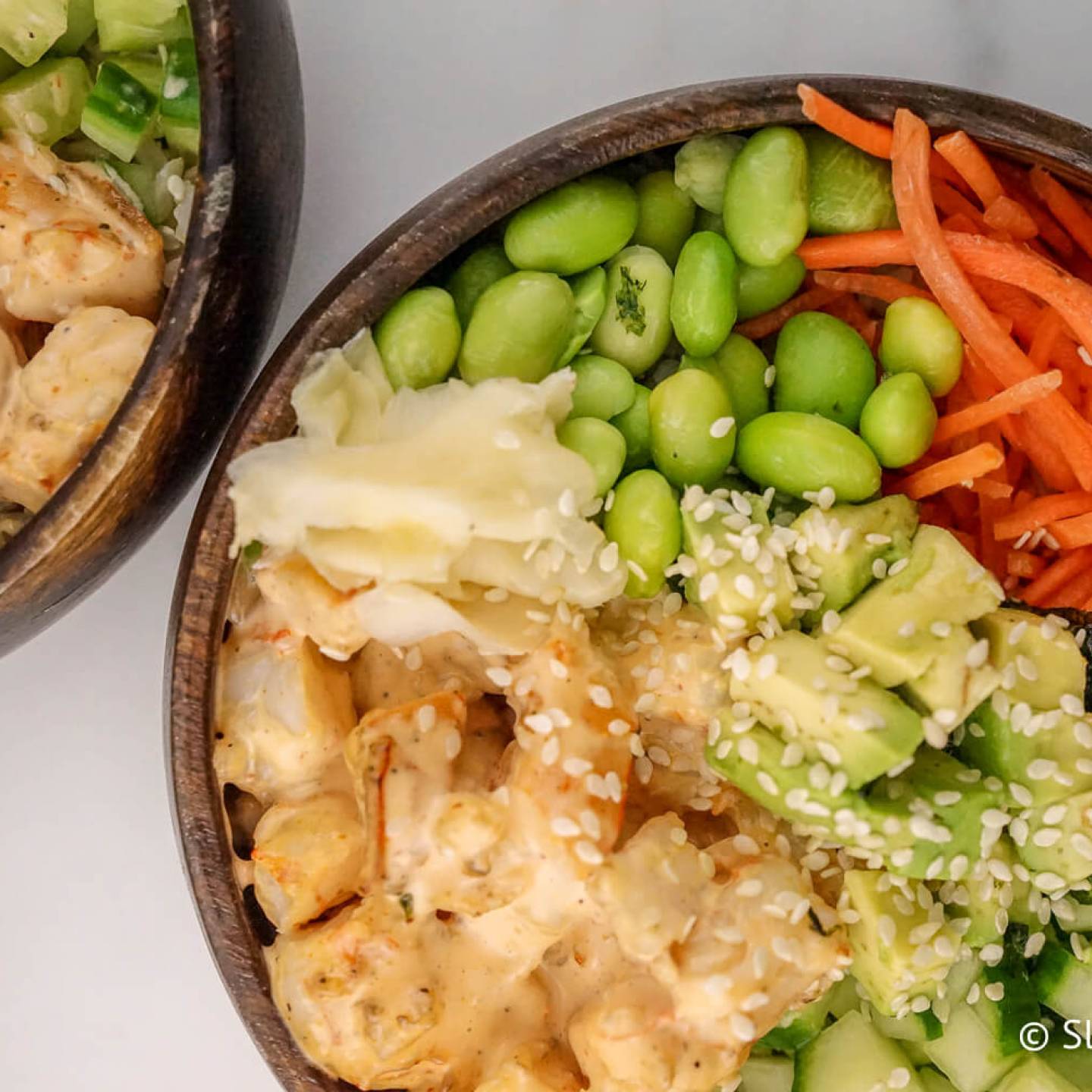 Sushi bowls with shrimp, cauliflower rice, avocado, cucumbers, and carrots.