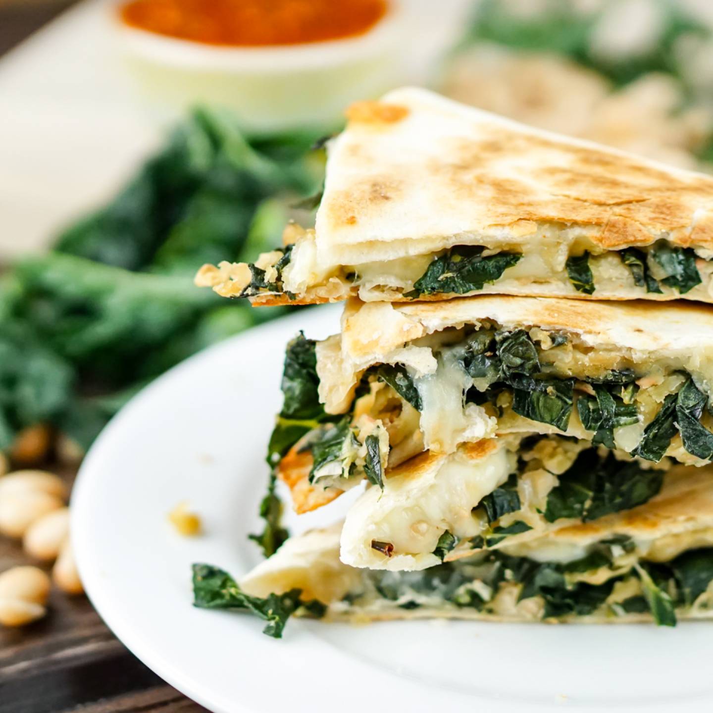 White bean and kale quesadillas stacked on top of each other with salsa and cilantro.