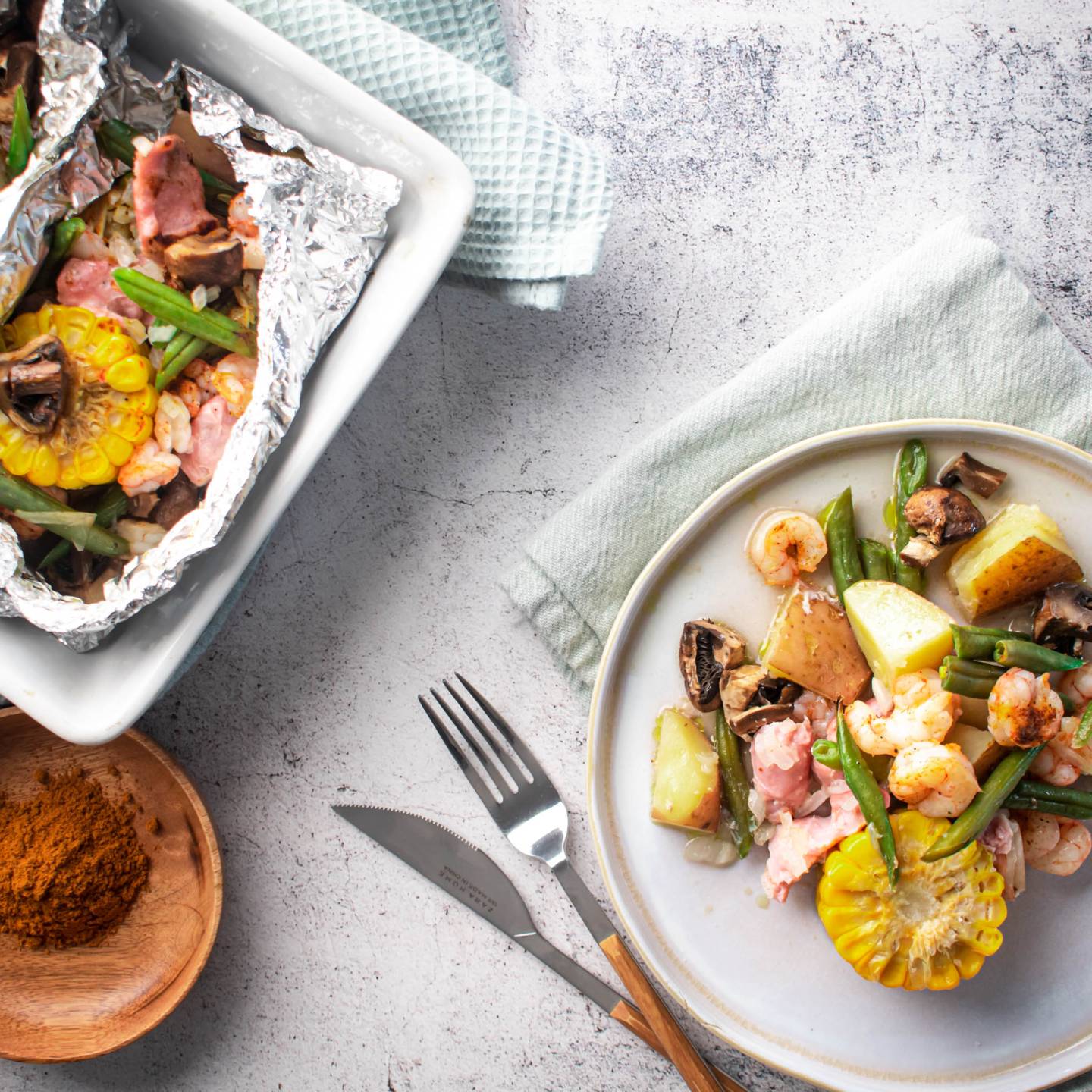 Shrimp boil foil packets with shrimp, andouille sausage, corn, green beans, potatoes, onions, and mushrooms in Cajun seasoning.