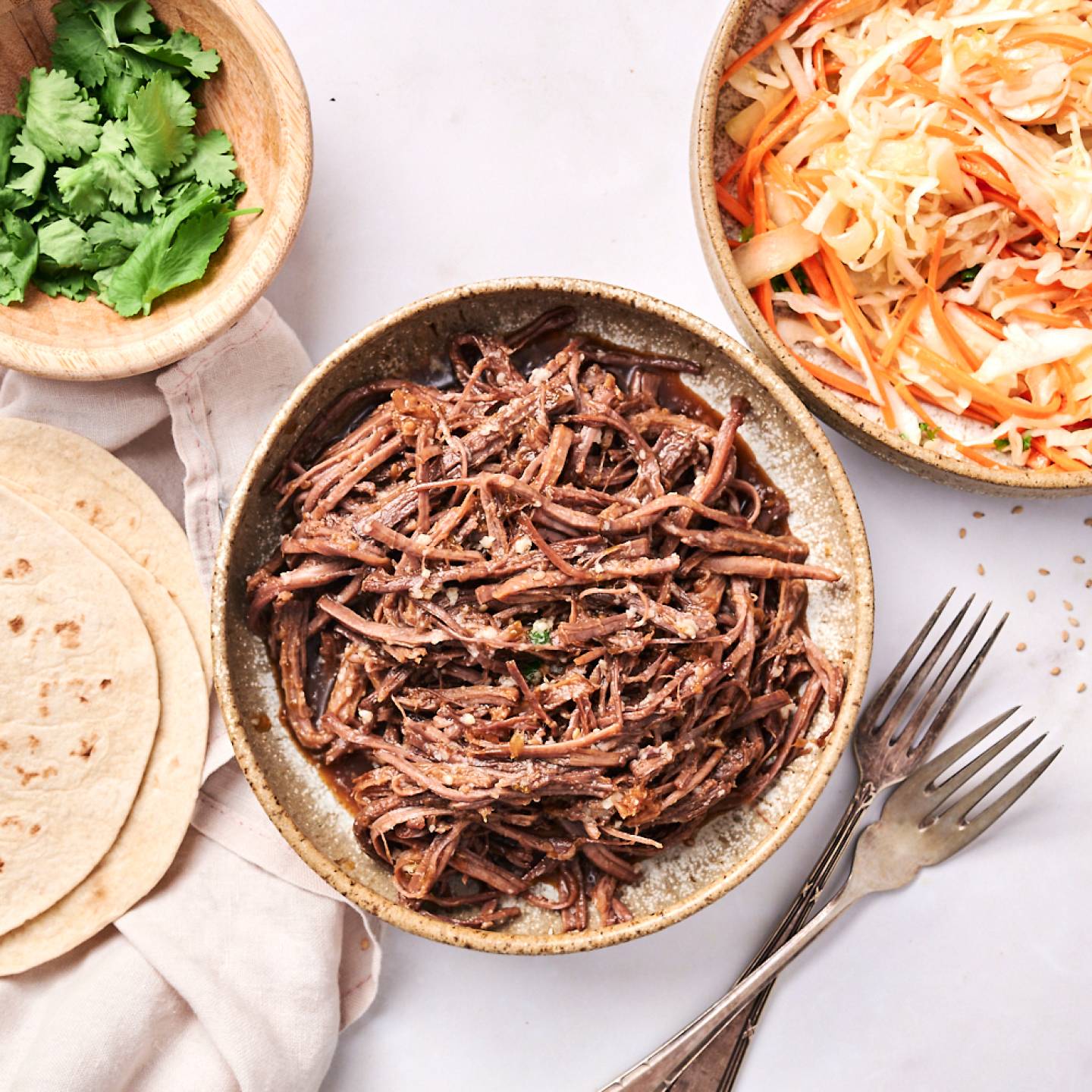 Slow cooker Korean beef tacos with corn tortillas, coleslaw, hot sauce, and Sriracha.