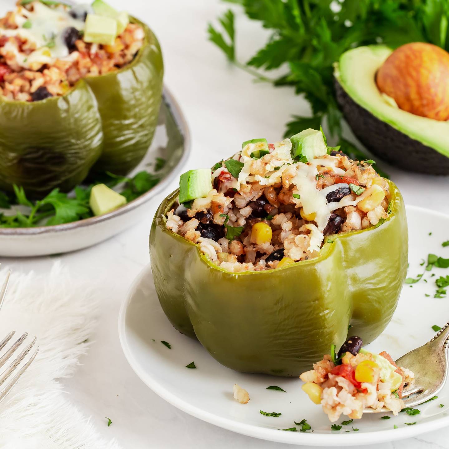 Slow cooker barbecue stuffed peppers with rice, beans, corn, onions, and diced avocado on a plate.