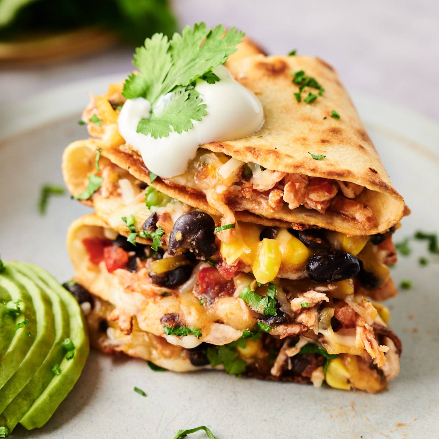 Spicy chicken quesadillas with shredded chicken, melted cheese, black beans, and corn in flour tortillas with sour cream, avocado, and cilantro.
