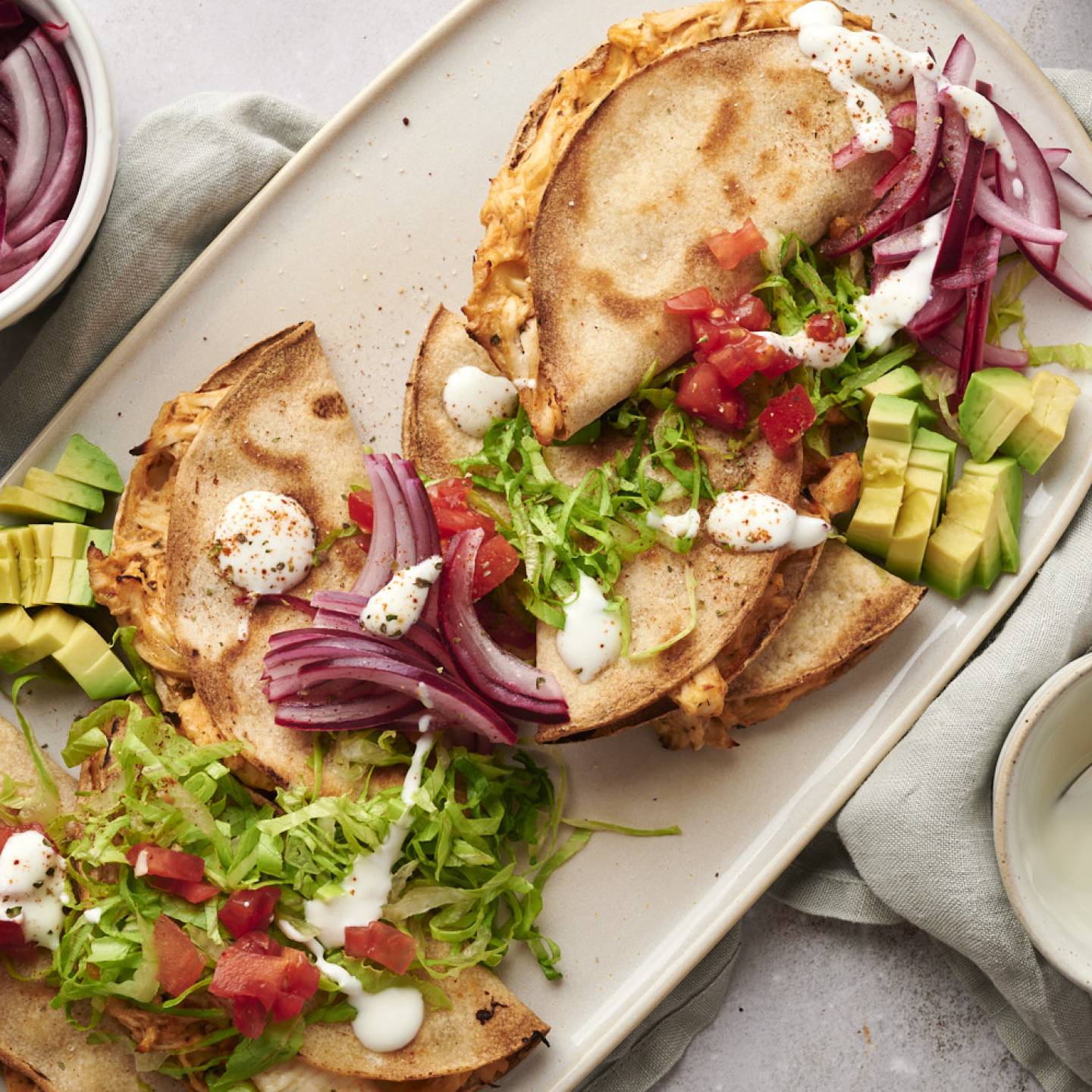 Tacos dorados filled with shredded chicken and served with avocado, onions, lettuce, salsa, and sour cream.