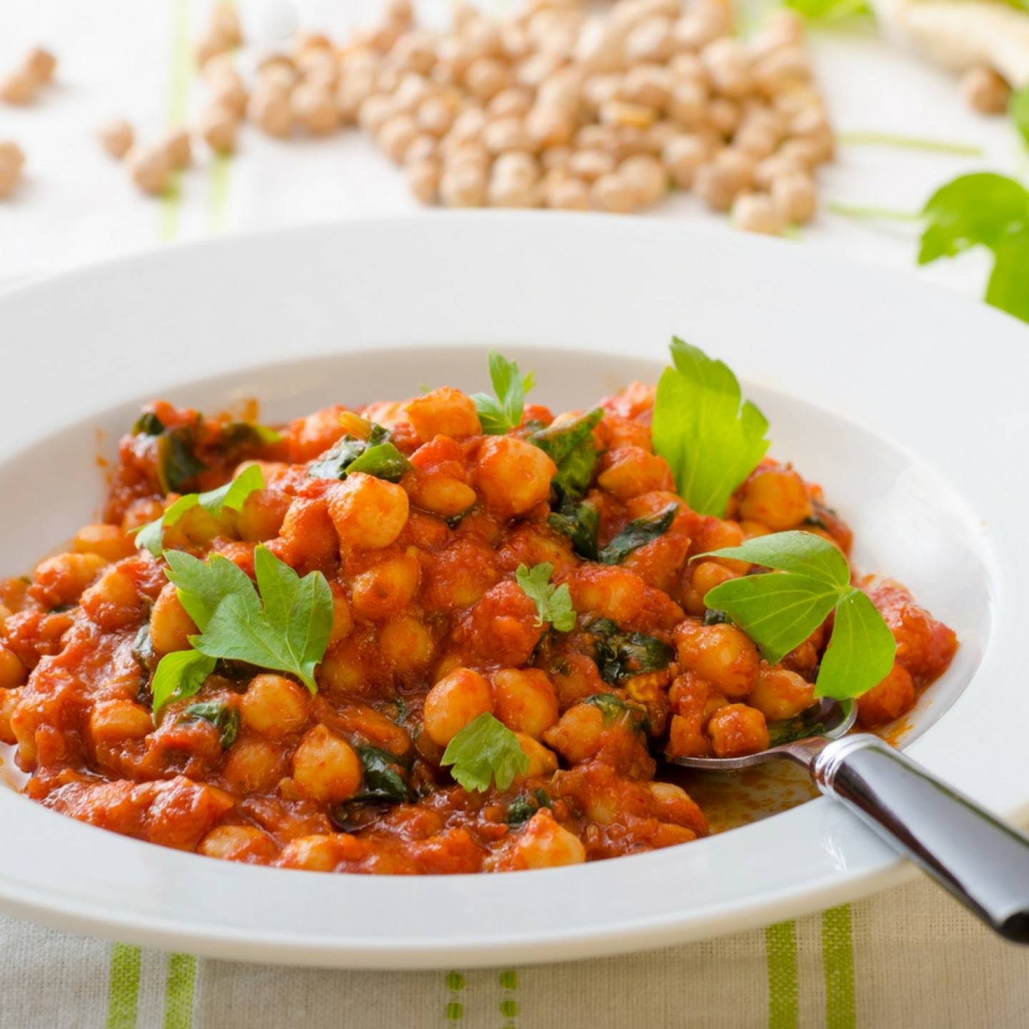Tomato coconut curry chickpea stew with coconut milk, tomatoes, chickpeas, spinach, and potatoes in a bowl.