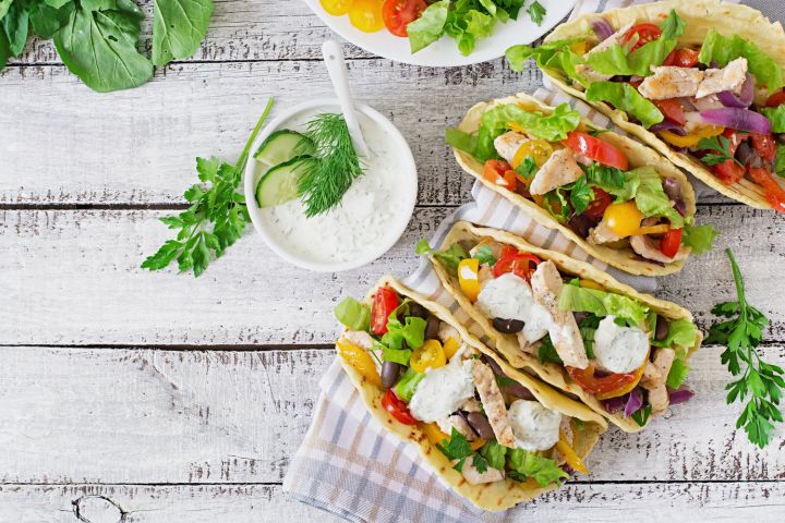 Chicken tacos with fresh vegetables on a gray cutting board for leftovers.