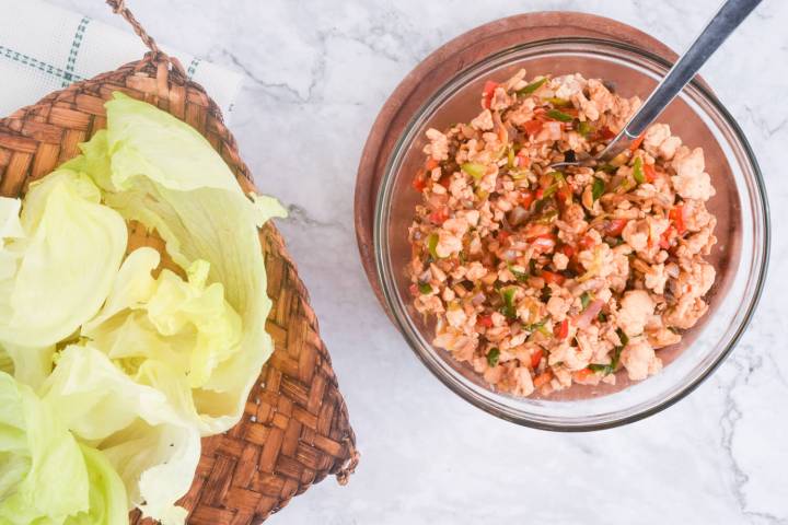 Bowl of chicken lettuce wrap filling and butter lettuce leaves.