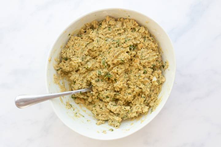 Falafel batter with mashed chickpeas, onion, garlic, and fresh herbs in a bowl.