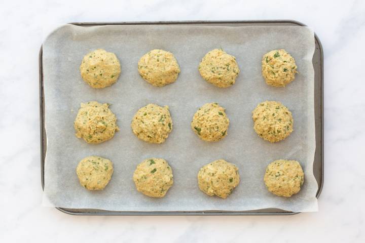 Falafel patties before being baked on a baking sheet with parchment paper.