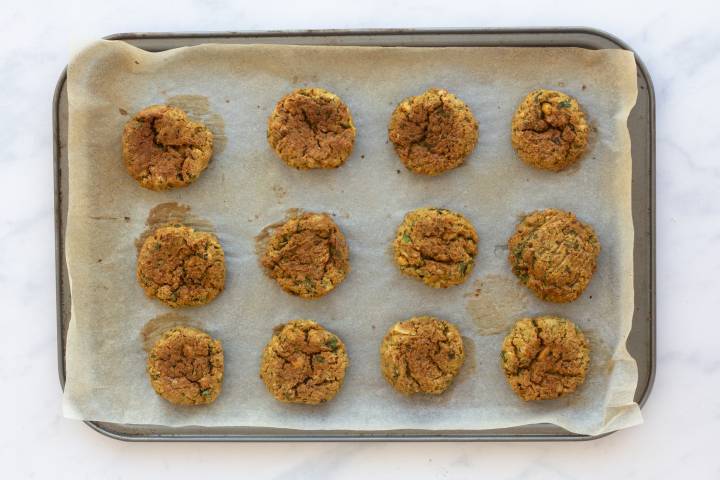 Baked golden brown falafel on a baking sheet.