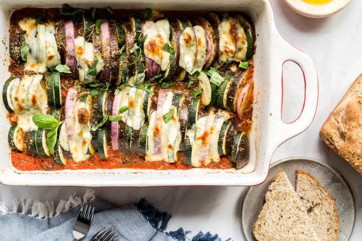 Baked ratatouille with melted mozzarella cheese served with bread.