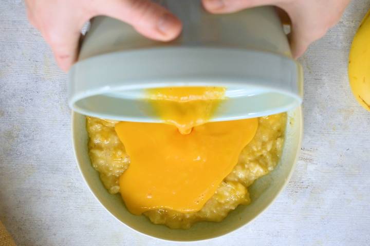 Mashed bananas being mixed with eggs and maple syrup.