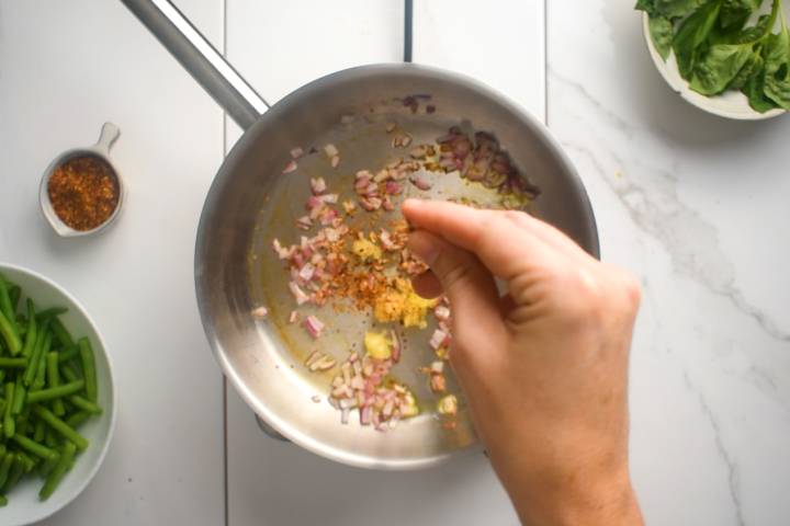 Garlic, red pepper flakes, and red onions in a skillet.