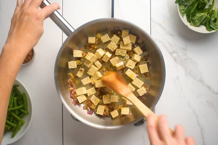 Tofu being cooked in a skillet in a single layer.