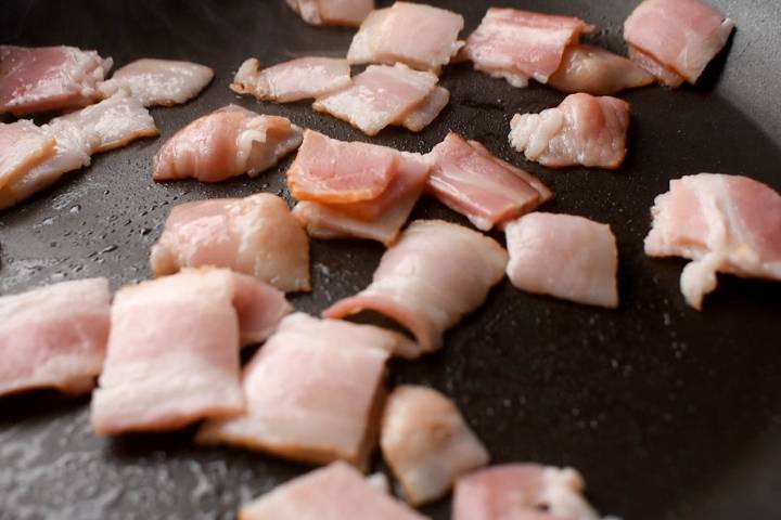 Chopped turkey bacon cooking in a skillet.
