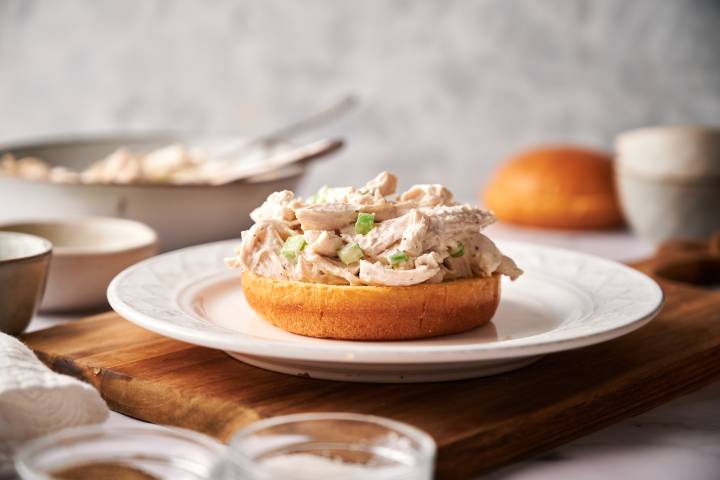 Sandwich being built with chicken salad on a brioche bun.