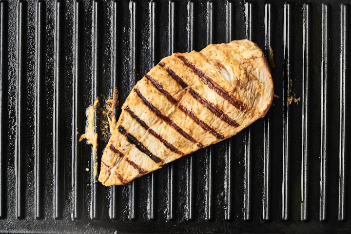 Grilled chicken breast with grill marks cooking on a grill pan.