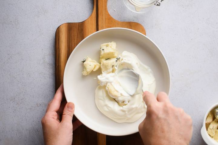 Gorgonzola cheese being mashed and stirred into Greek yogurt.