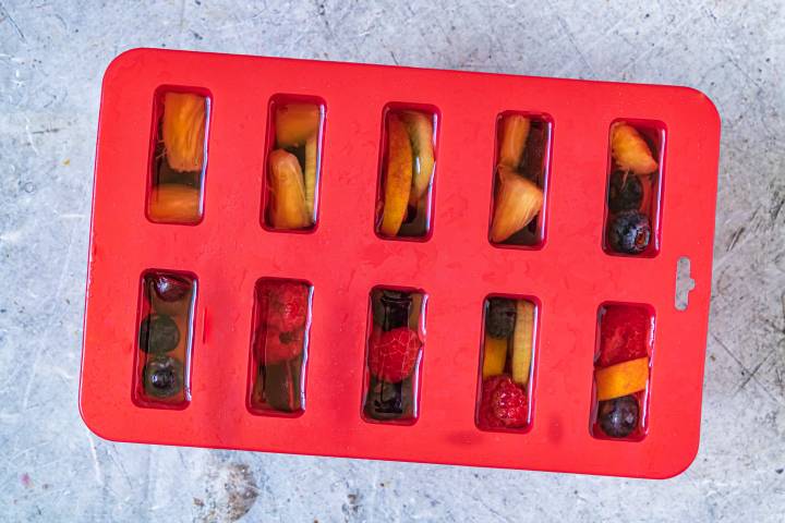 Fresh fruit popsicles with coconut water in a popsicle mold.