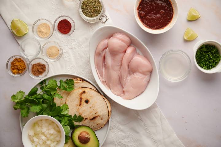 Chicken breasts cut into thin slices with ingredients for taco marinade.