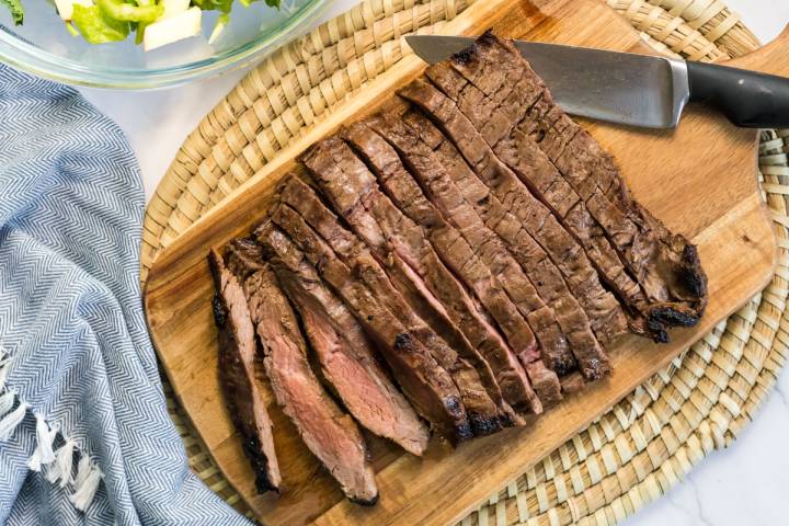 Grilled flank steak sliced thin on a cutting board.