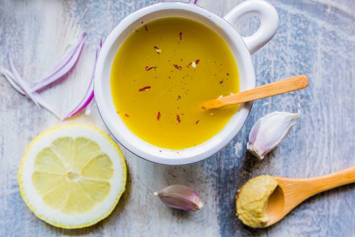 Honey and lemon dressing in a small bowl with lemon on the side.