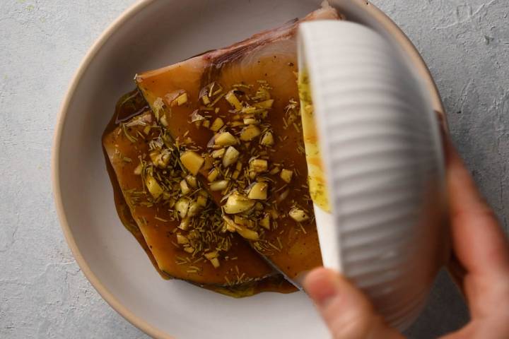 Swordfish being marinated in lemon garlic sauce.