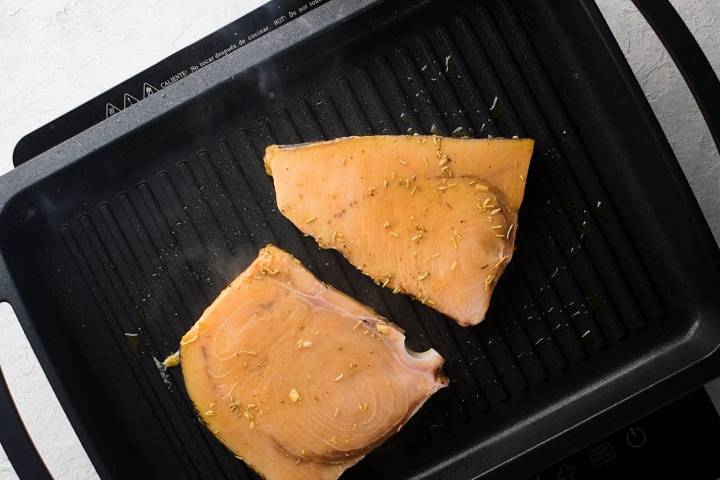 Swordfish steaks on the grill with olive oil.