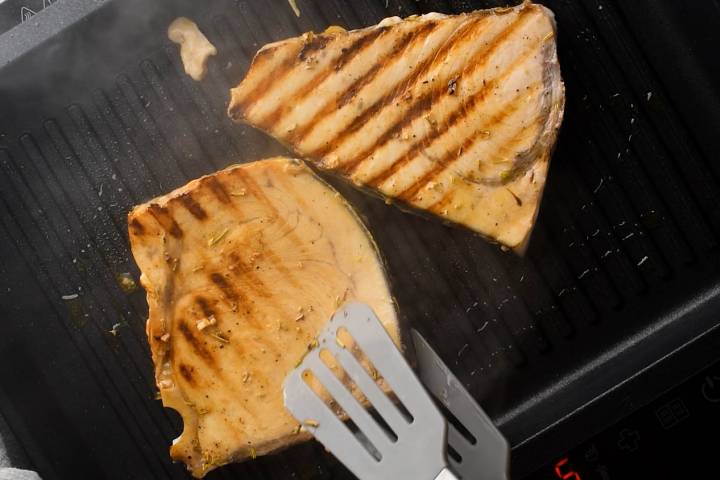 Grilled swordfish steaks with grill marks on a grill pan.