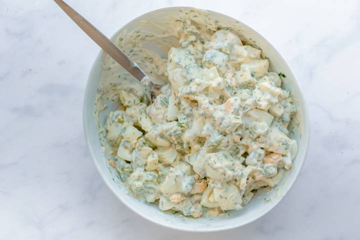 Healthy egg salad mixed together in a bowl with a spoon.