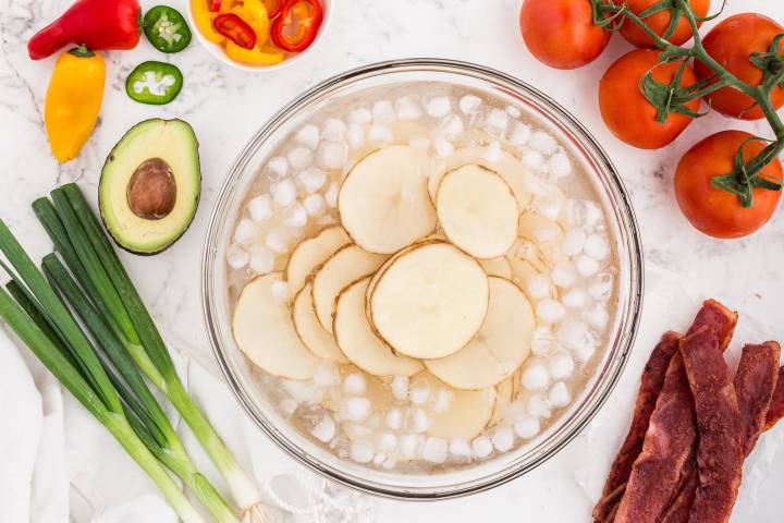 Sliced potatoes sitting in an ice bath.