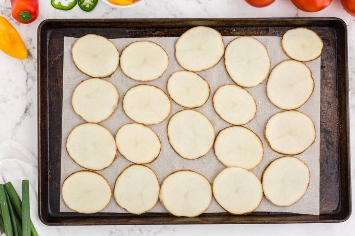 Sliced potatoes on a baking sheet with parchment paper.