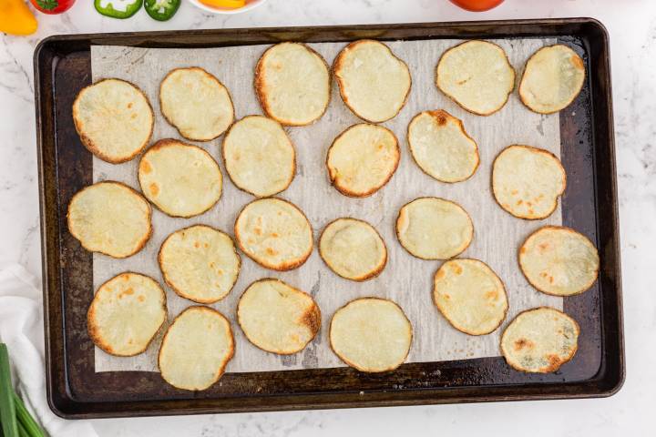Crispy baked potato chips on a baking sheet with parchment paper.