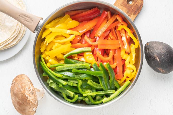 Sliced bell peppers and red onions in a bowl.