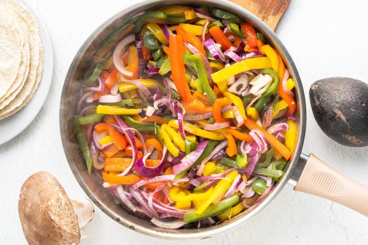 Cooked bell peppers and onions in a skillet.