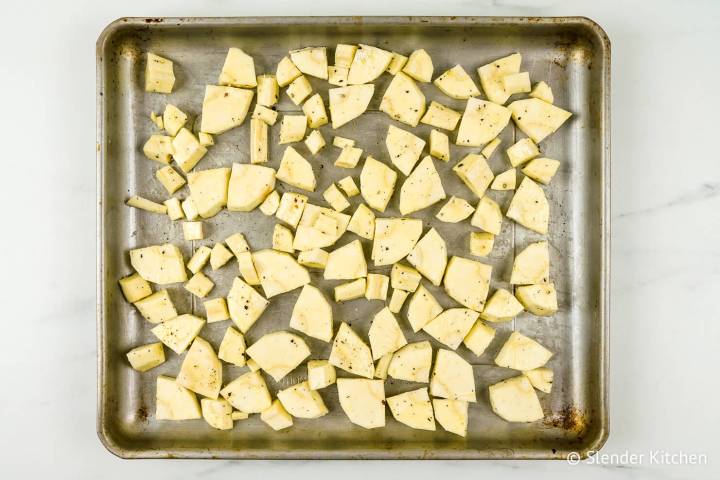 Parsnips tossed with olive olive oil and spices on a baking sheet.