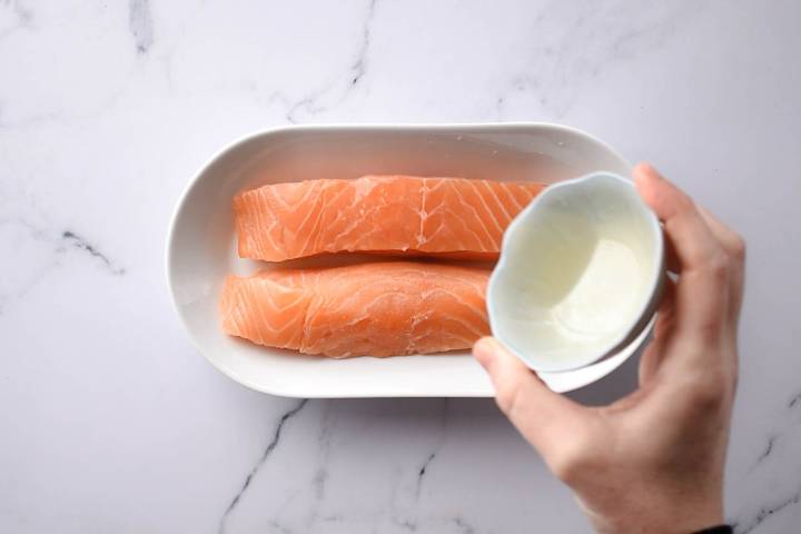 Salmon with lemon juice being poured on top.