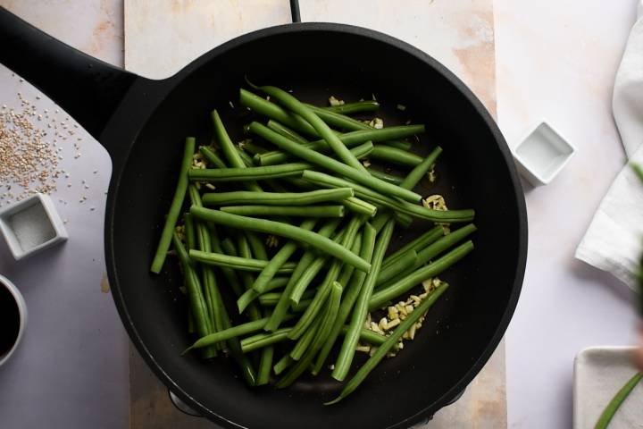 Green beans, soy sauce, and garlic in a cast iron skillet.