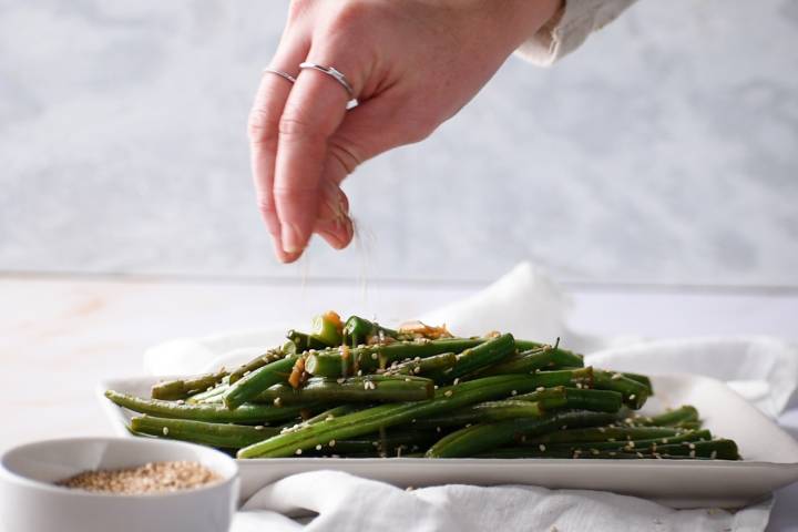 Sesame seeds being added to Asian green beans.