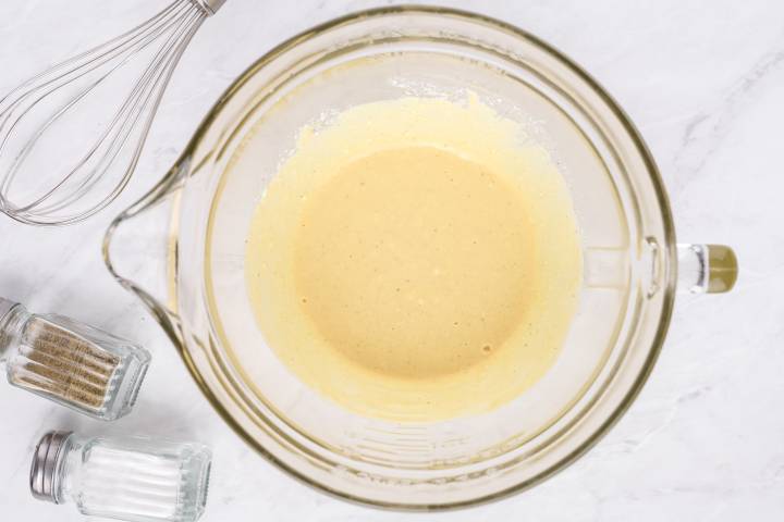 Honey dijon dressing in a glass measuring cup with a whisk.