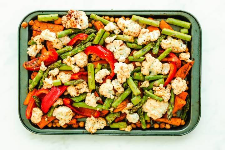 Vegetables, chickpeas, and sweet potatoes on a baking sheet.