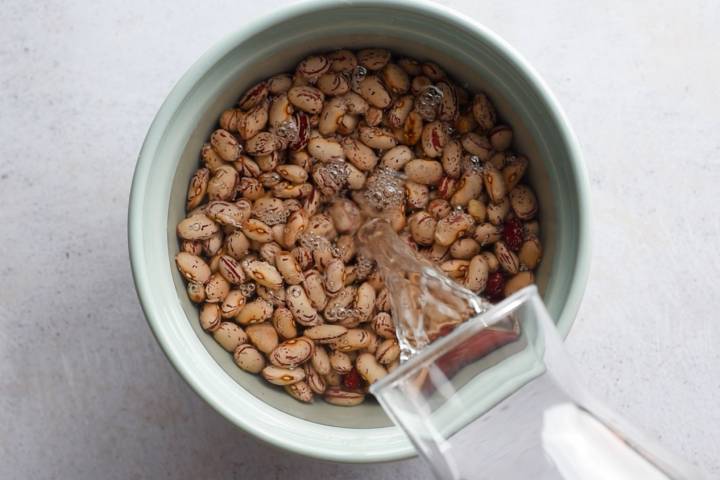 Pinto beans soaking in a bowl in water.
