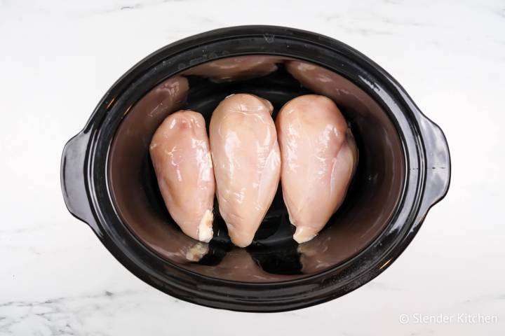 Boneless skinless chicken breasts in a slow cooker.