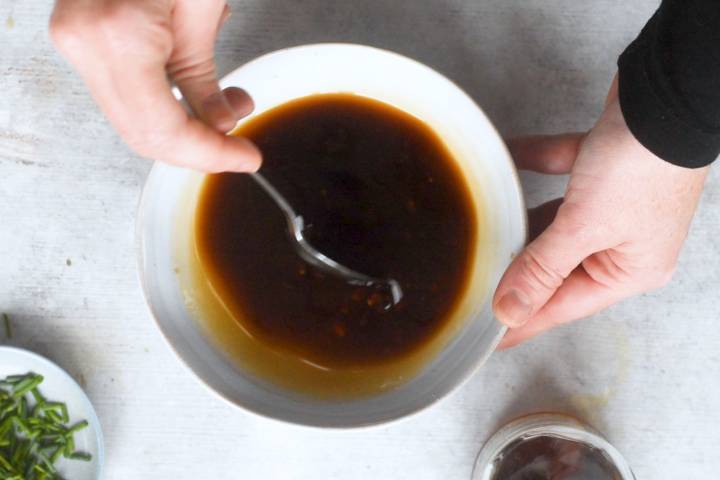Sauce for chicken lettuce wraps being stirred in a white bowl.