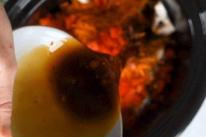 Browned chicken, vegetables, and sauce in a slow cooker for lettuce wraps.