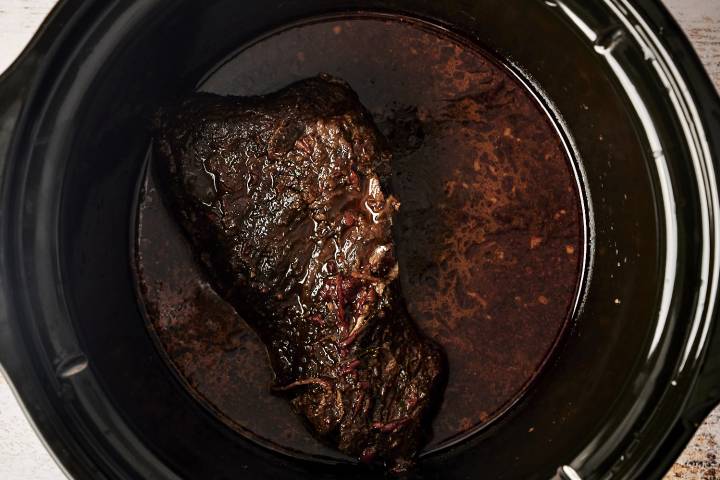 A slow-cooked beef roast is infused with rich adobo sauce, tender and ready to be shredded for a flavorful Mexican dish.